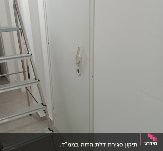 דלת לבנה עם מנעול ומדרגות מתכת בצד